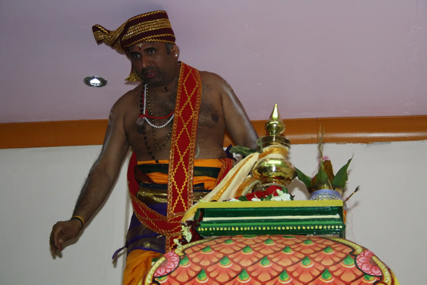 A priest with the kalasam, dressed and standing ready.