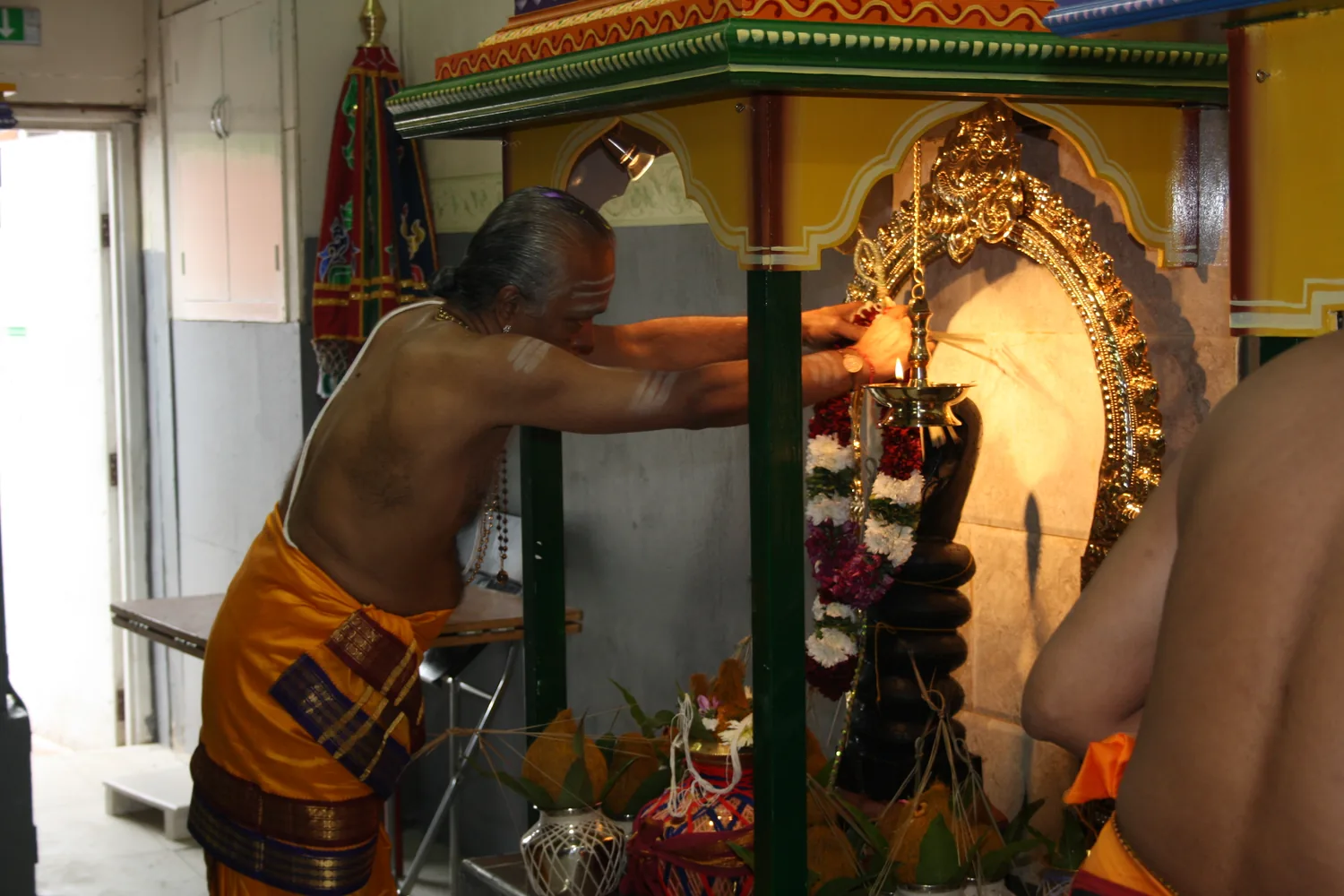 A priest at the shrine, the deity garlanded.
