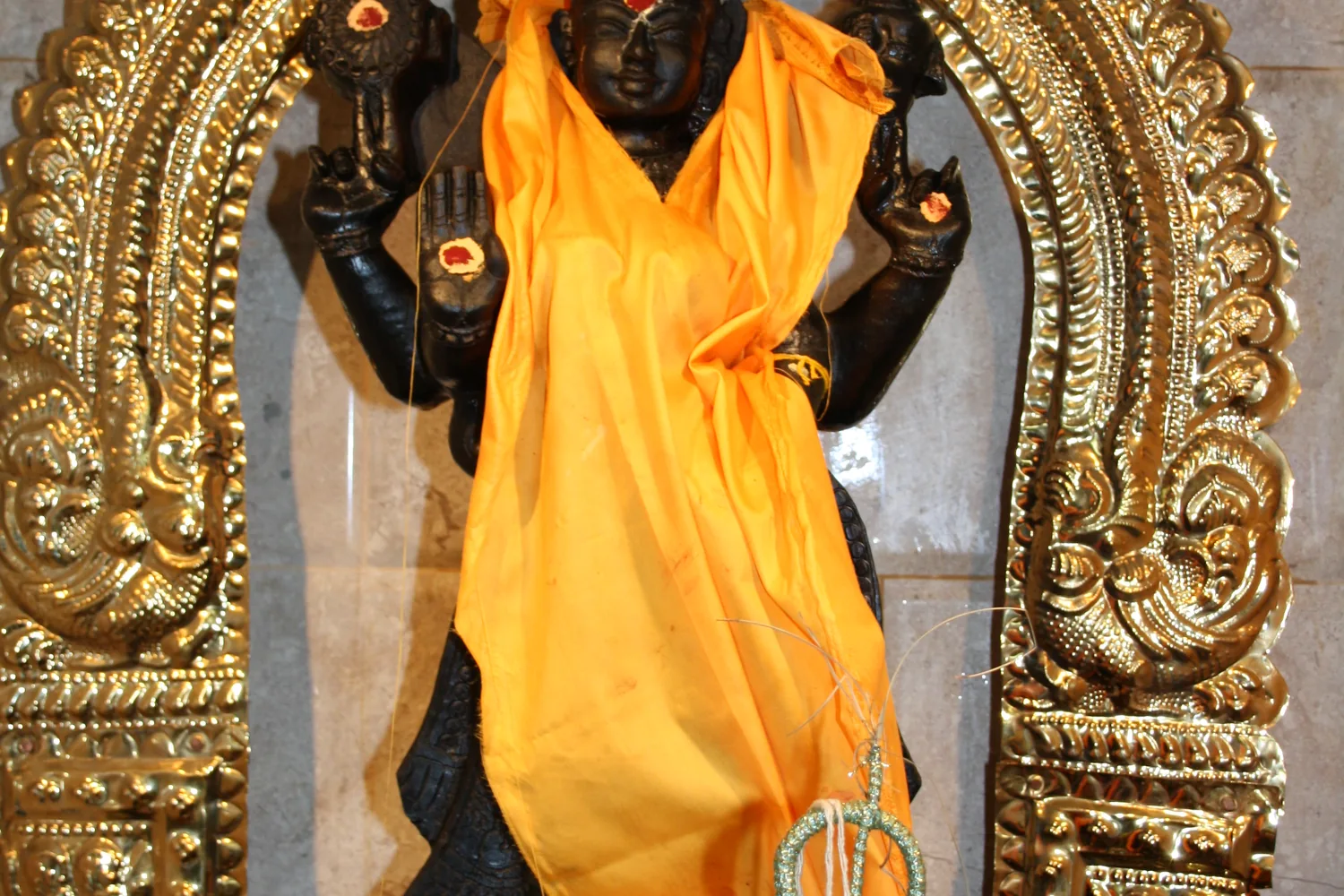 A deity in the gold arch, dressed in saffron.