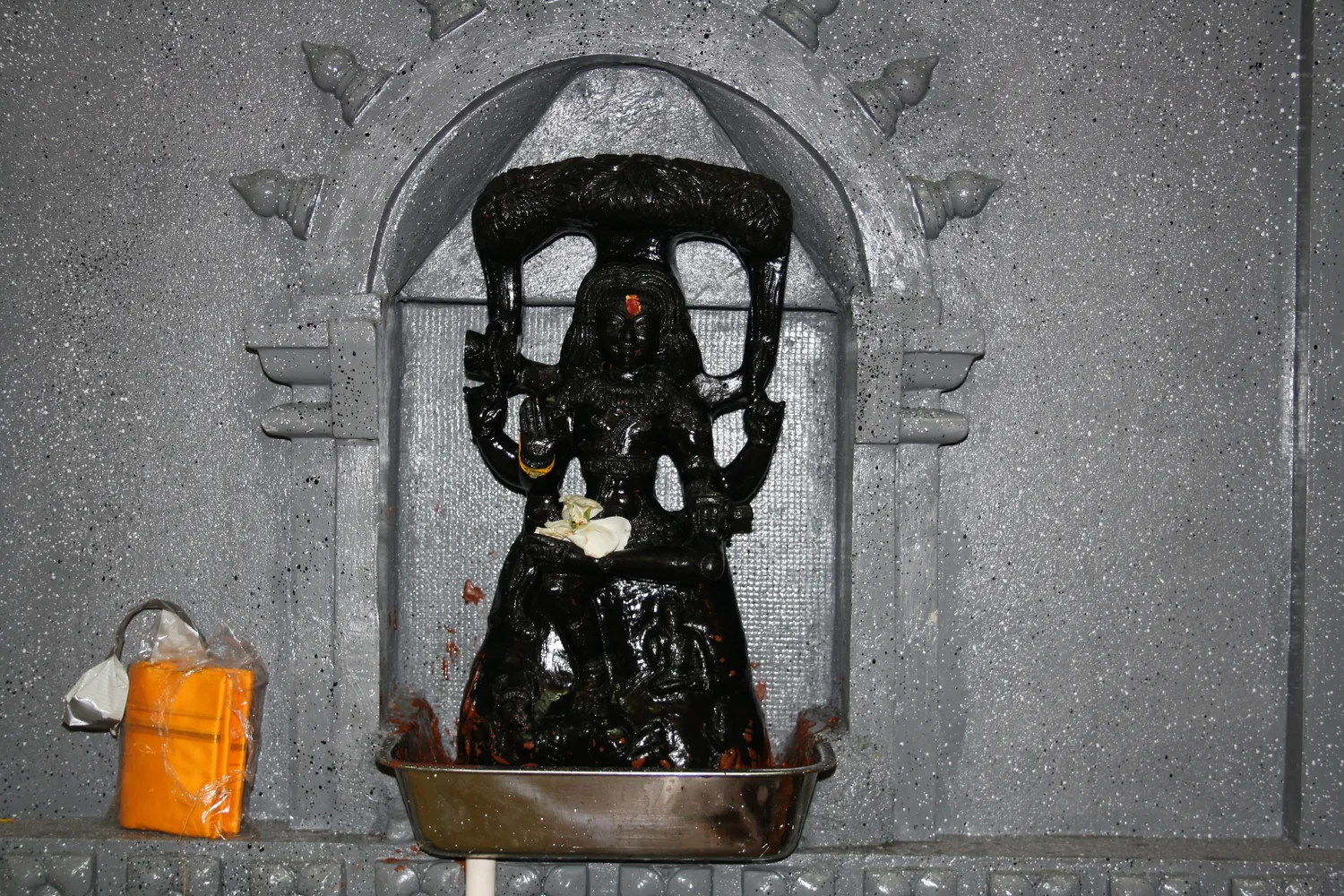 A stone deity in its granite niche.